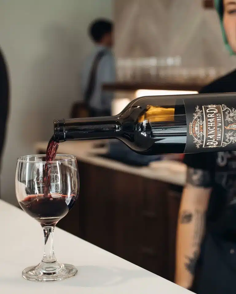 A staff member at Blanchard Family Wines pouring a glass of red