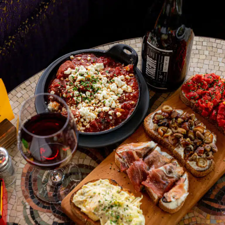 A Postino bruschetta board served with a glass of red wine