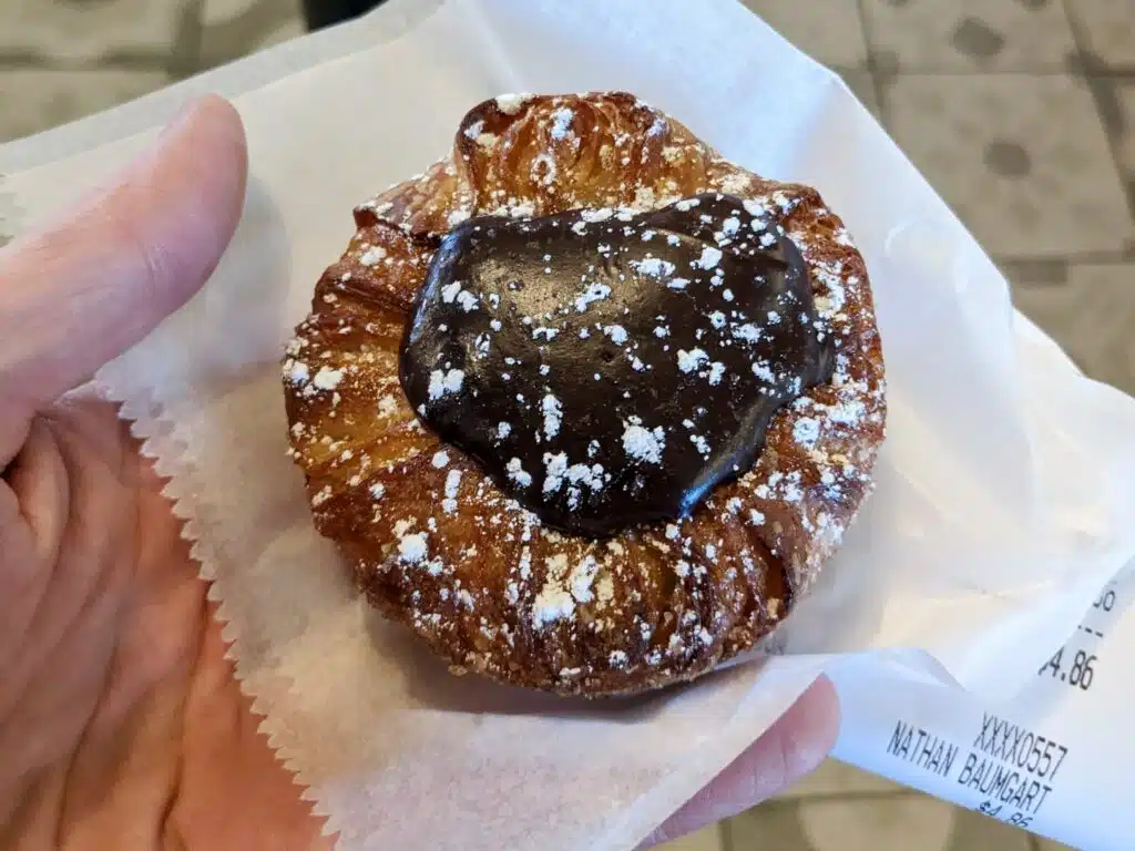 Nate, founder of Delicious Denver Food Tours, holding a chocolate Colorado Queen from Izzio Bakery