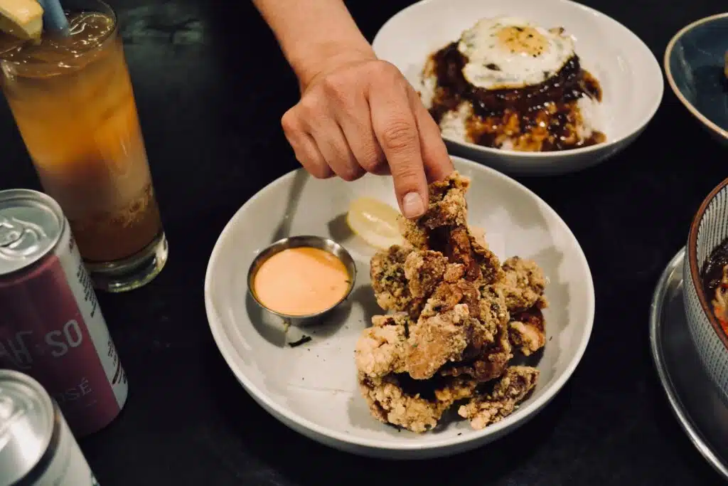 A person reaching for a piece of fried chicken kara'age at Osaka Ramen