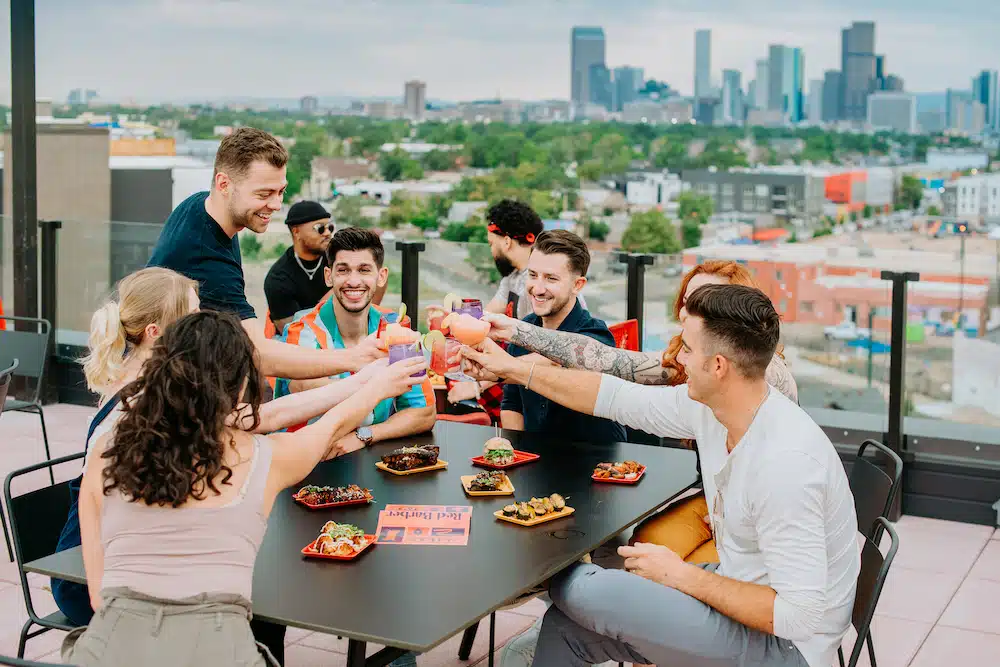 A group toasts cocktails on the Red Barber rooftop