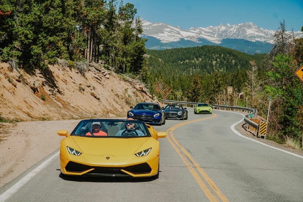 A fleet of Oxotic Supercars driving through the Rocky Mountains