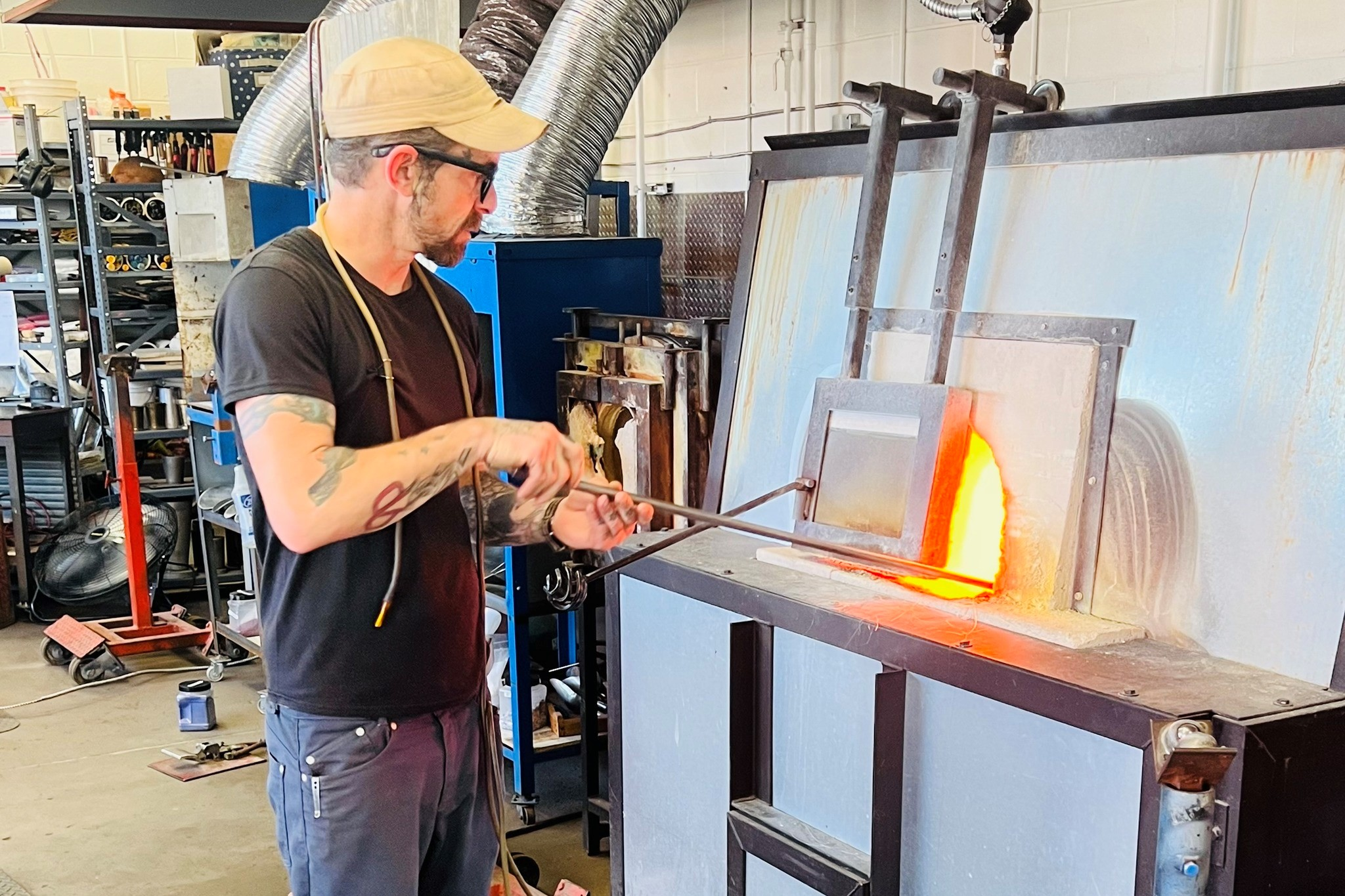 An artist turning glass in a kiln at The Furnace