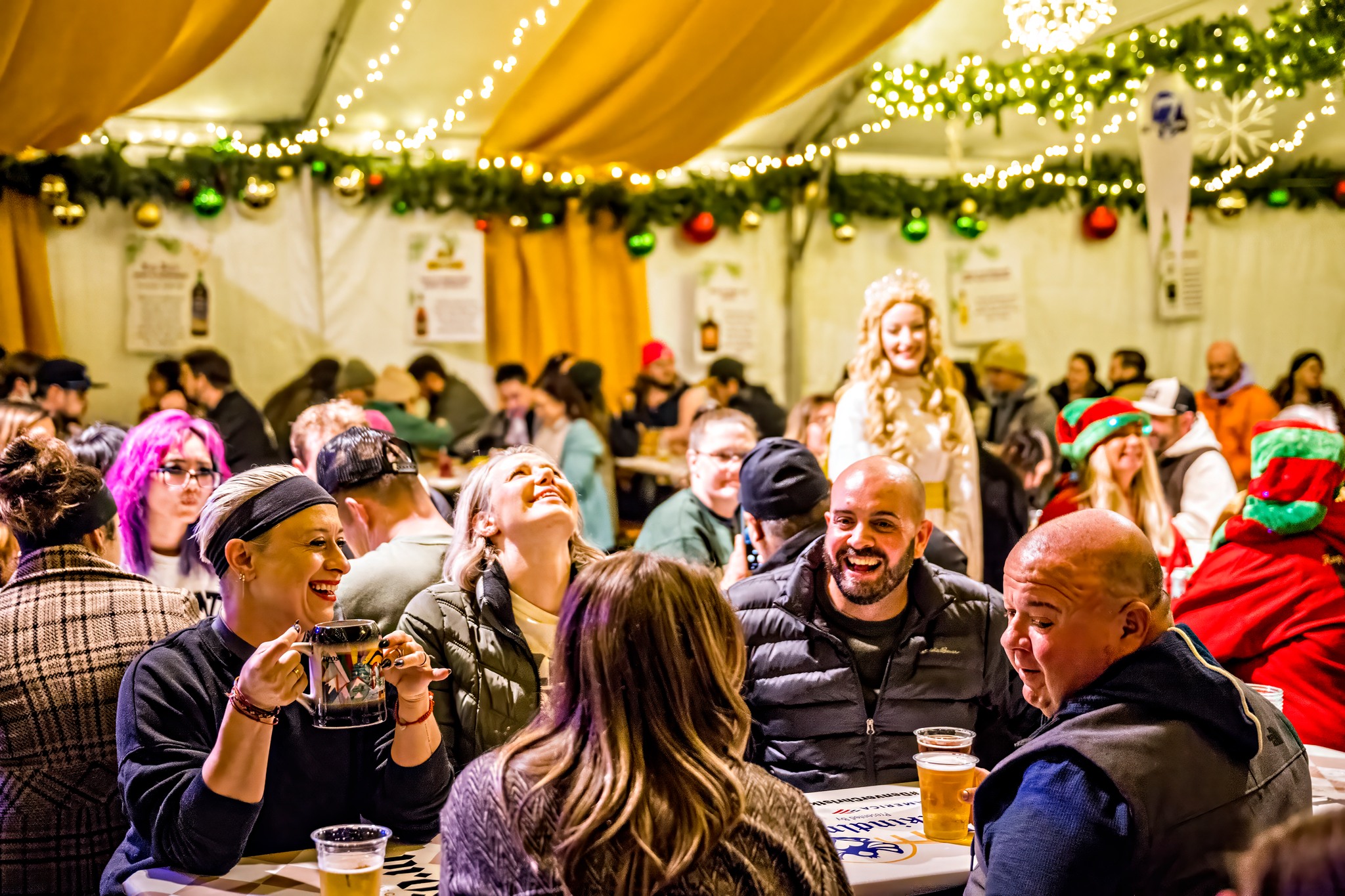 people laughing inside tent at christkindle market in denver