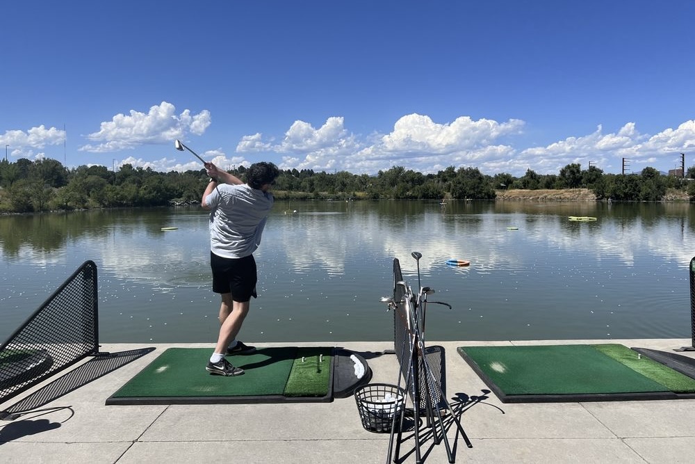 A man taking a swing from the waterfront driving range at Aqua Golf