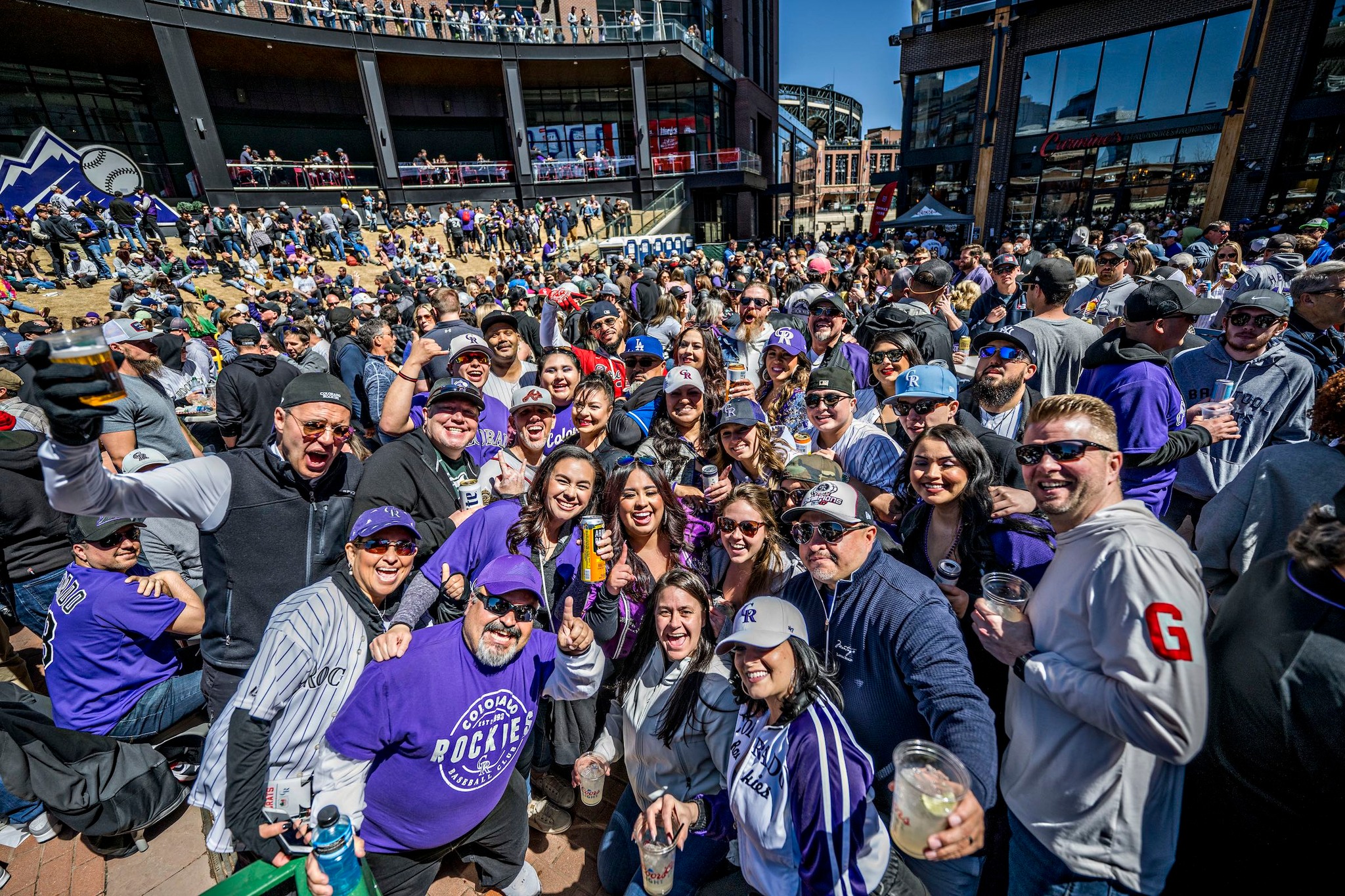 A massive crowd of Rockies fans smiling to camera in McGregor Square