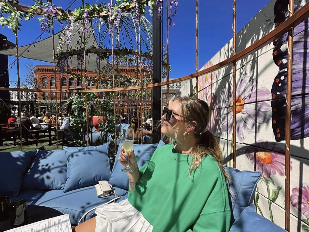 A woman seated within one of the unique birdcage booths at Wonderyard