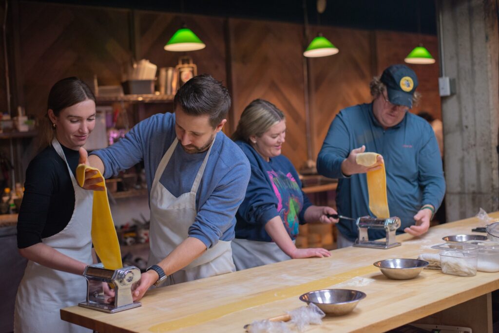 Co-workers learning to craft handmade pasta during a Cook Street School of Culinary Arts class