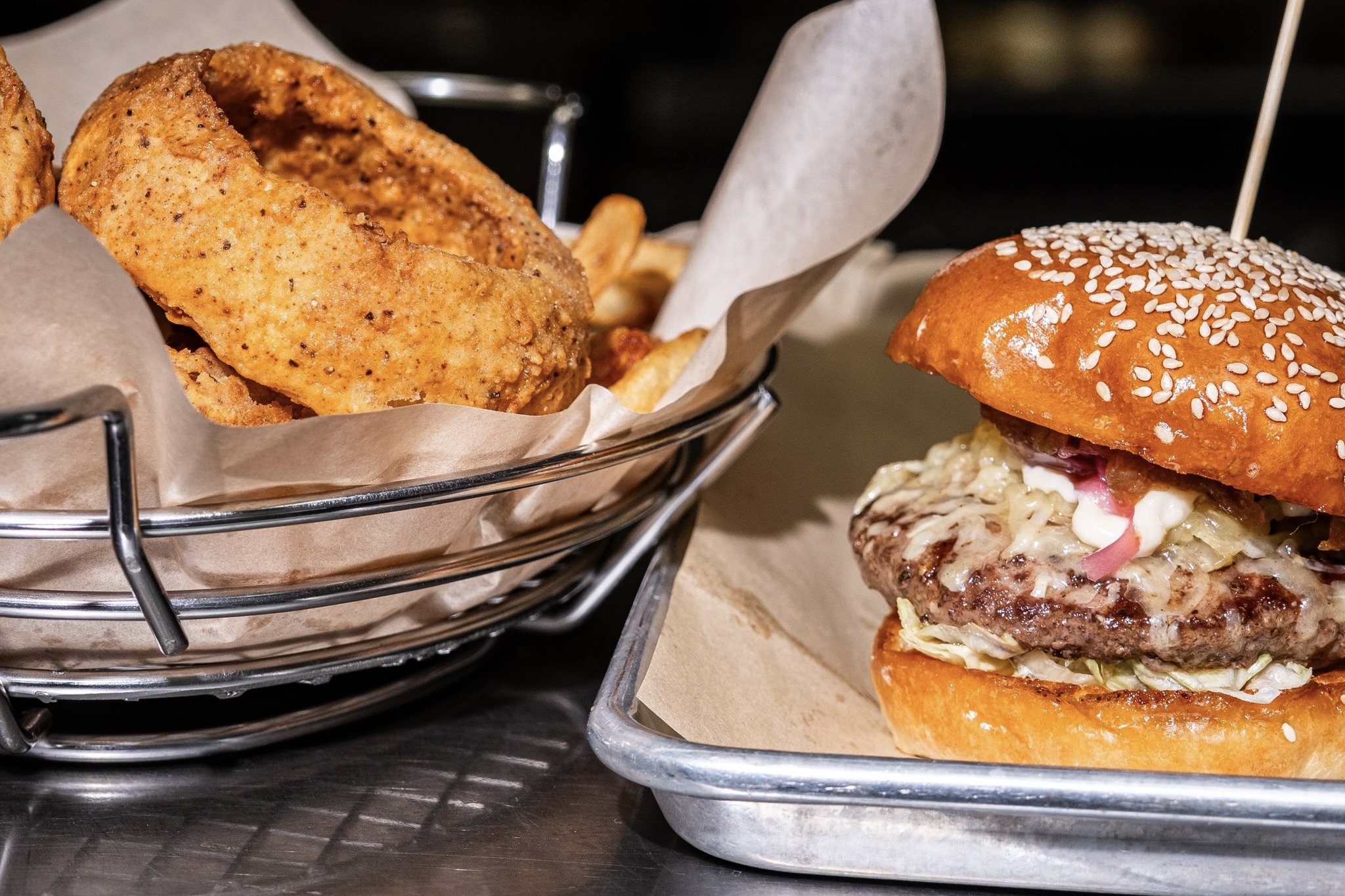 A 5280 signature burger next to a basket of onion rings