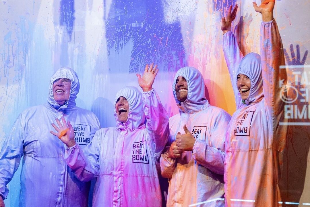 Four smiling people in paint-covered hazmat suits at Beat the Bomb
