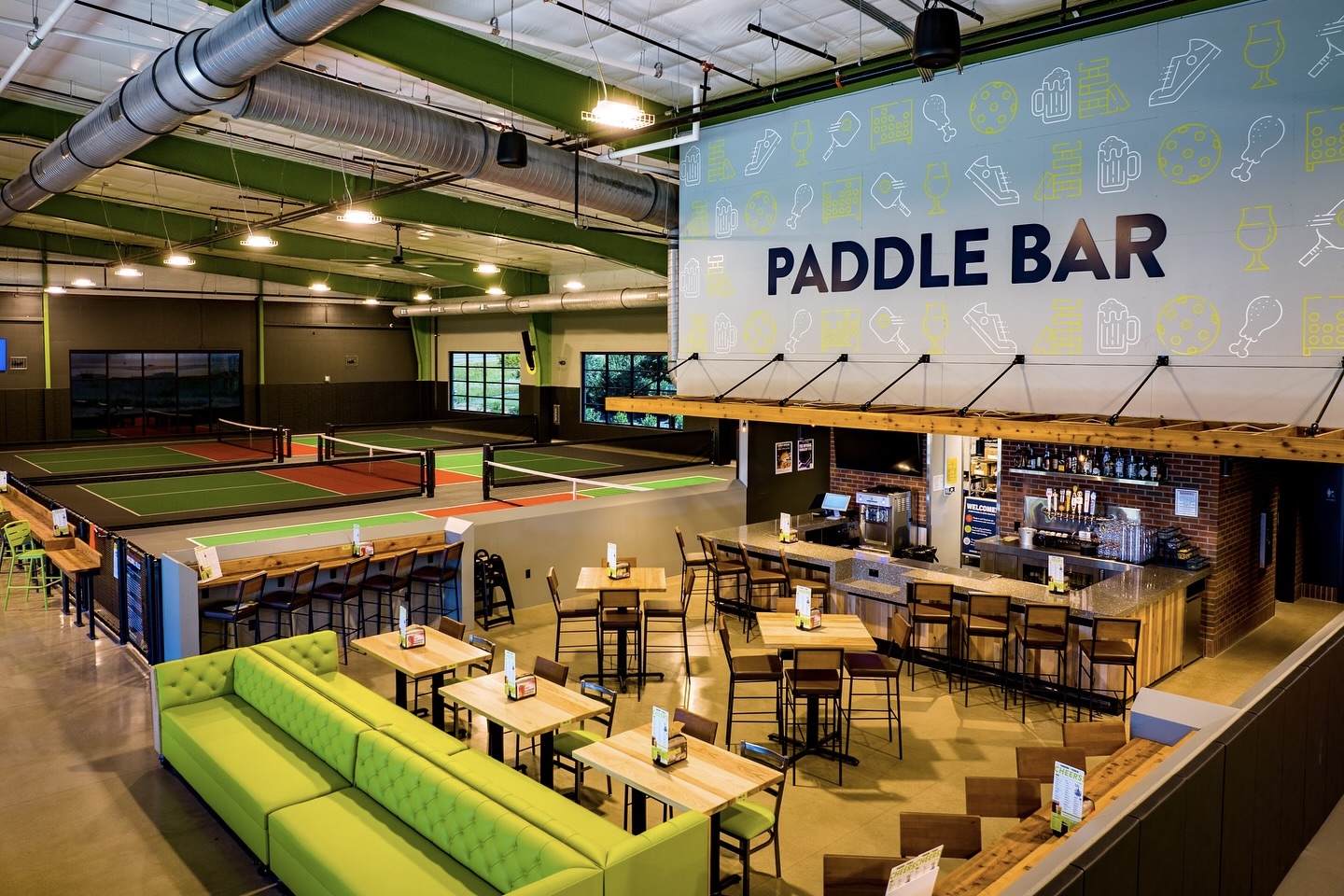 Indoor pickleball courts and a lounge area within Chicken N Pickle Thornton