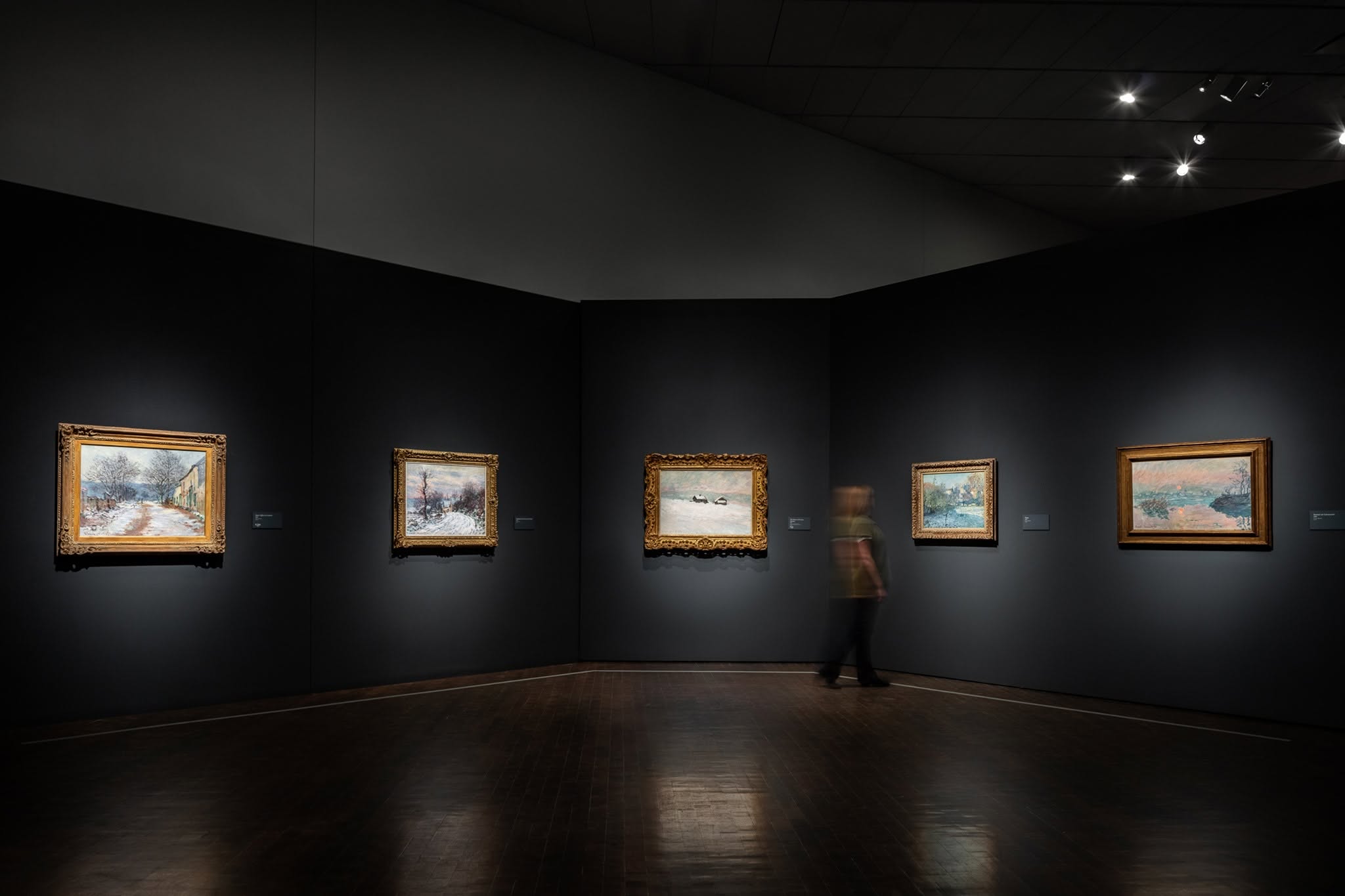 A person inside a dimly lit gallery at the Denver Art Museum