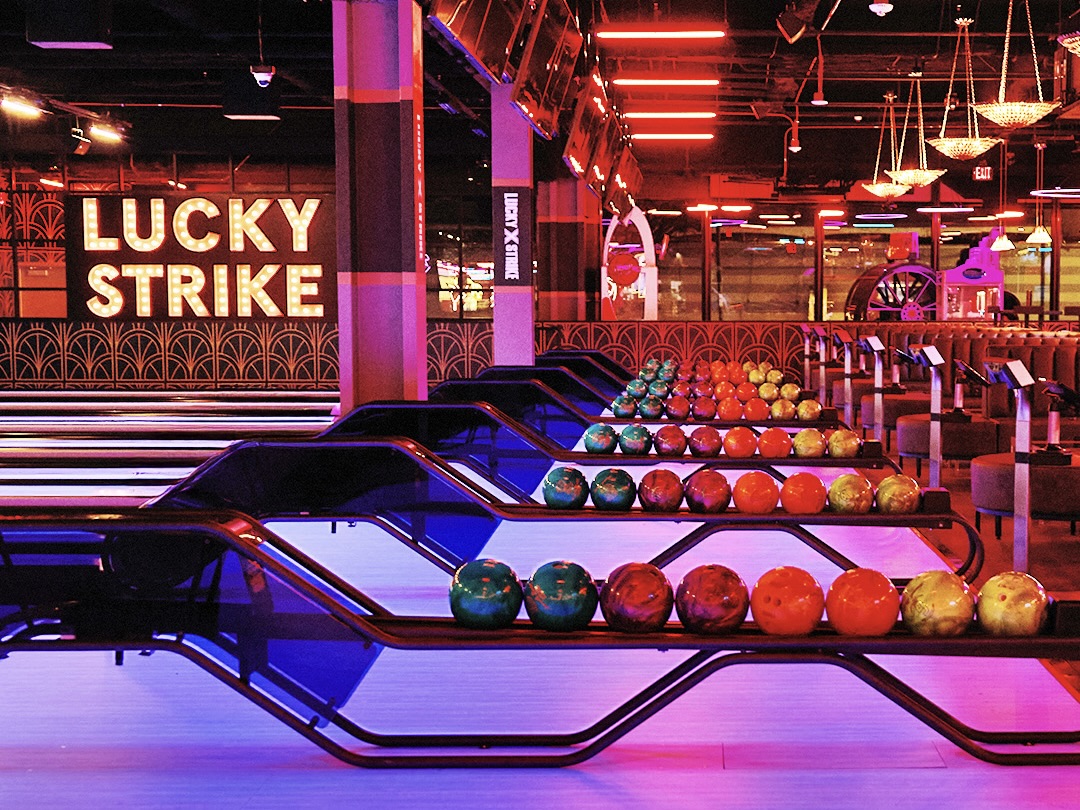 Bowling lanes within Lucky Strike illuminated under pink neon lights