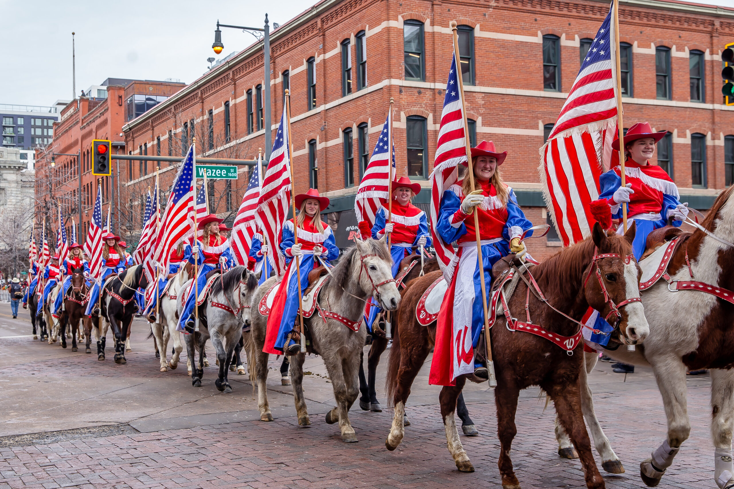 People holding American flags on horseback during the National Western Stock Show