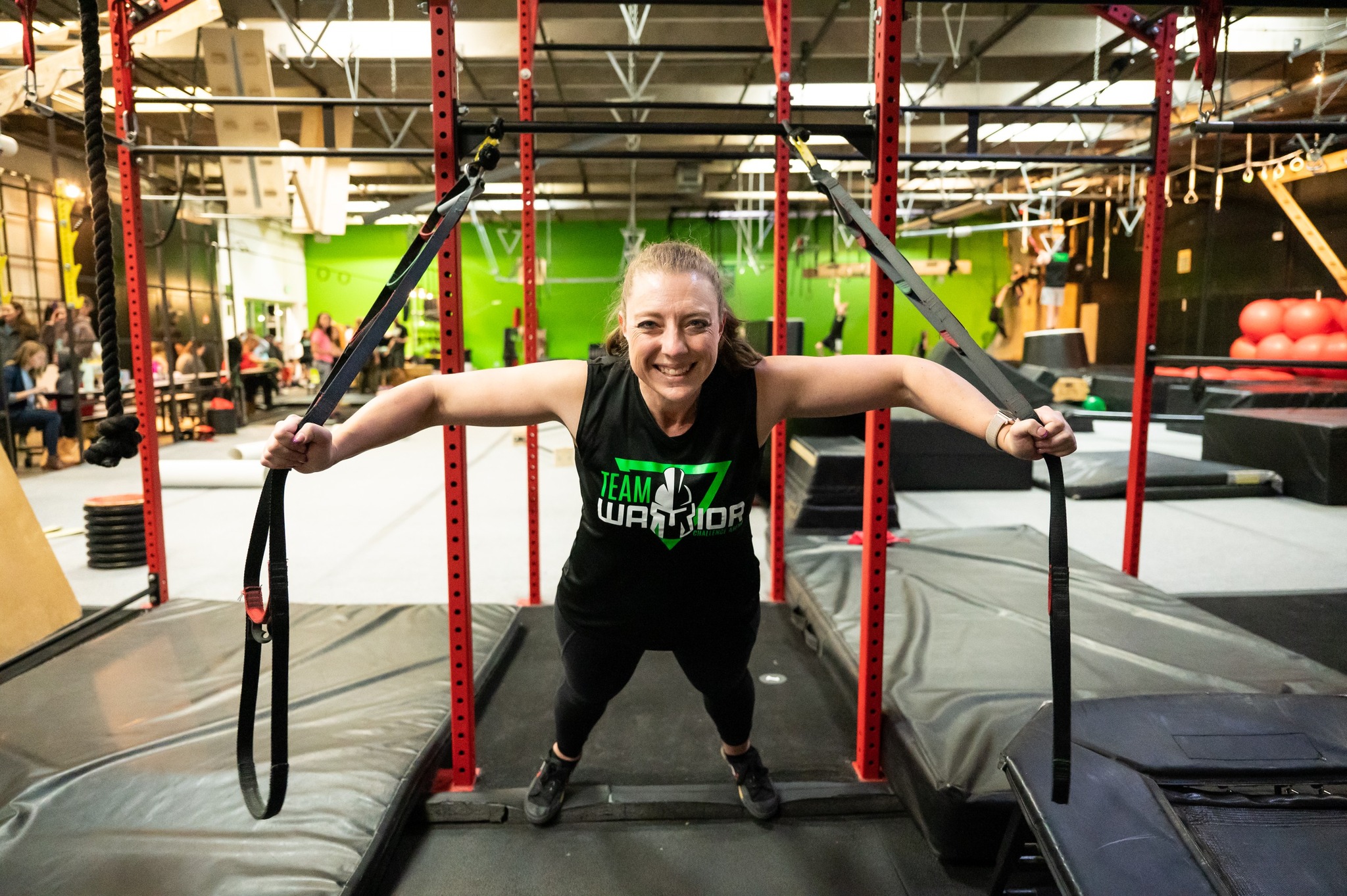 A woman leaning forward on gym equipment within Warrior Challenge Arena 