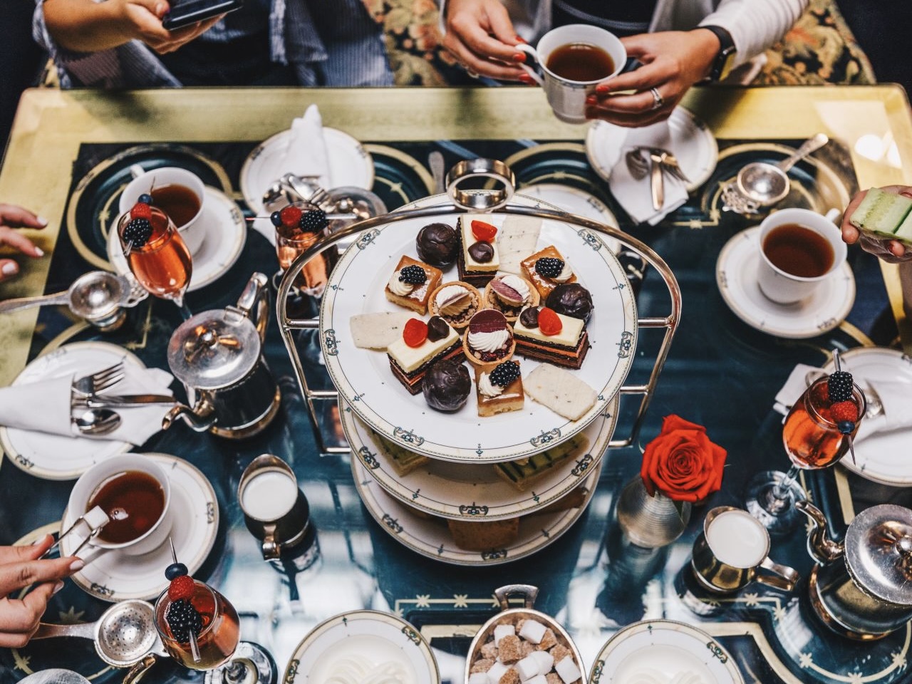 Tea pots, glasses of rosé, and a tiered display of bites served during afternoon tea at The Brown Palace