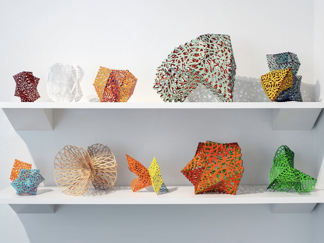 Vibrant, geometric shapes resting on a white shelf inside Robischon Gallery