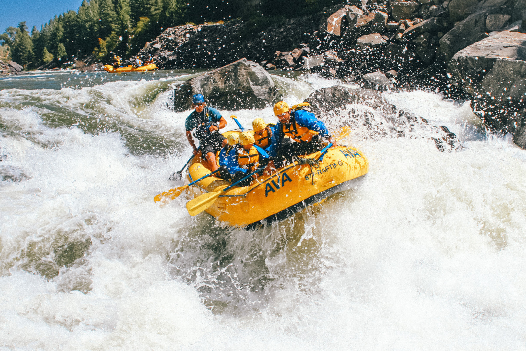An AVA Rafting tour group paddling through Clear Creek rapids