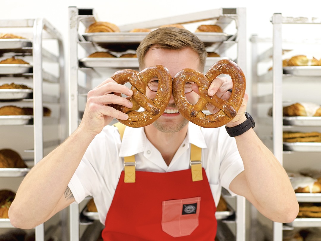 A Rebel Bread baker holding up two pretzels