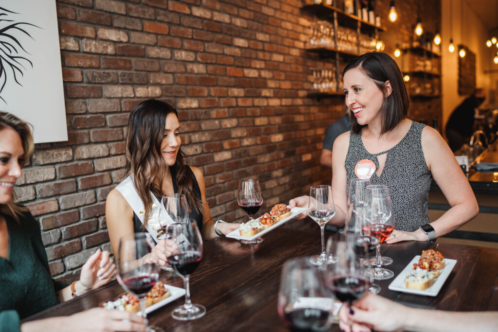 tour guide serving tasting to women at table on delicious denver food tours downtown dinner tour