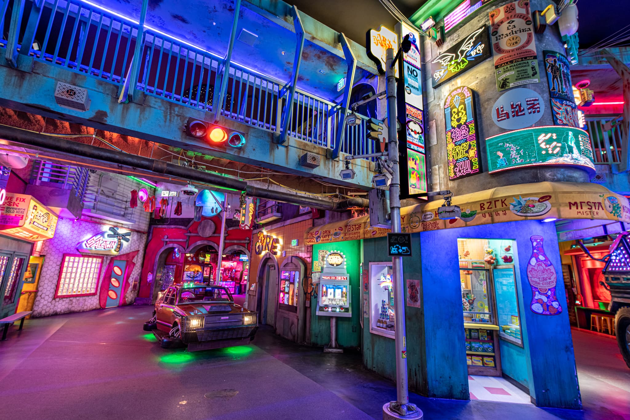 Neon lights and vibrant signs within a Meow Wolf Convergence Station exhibit
